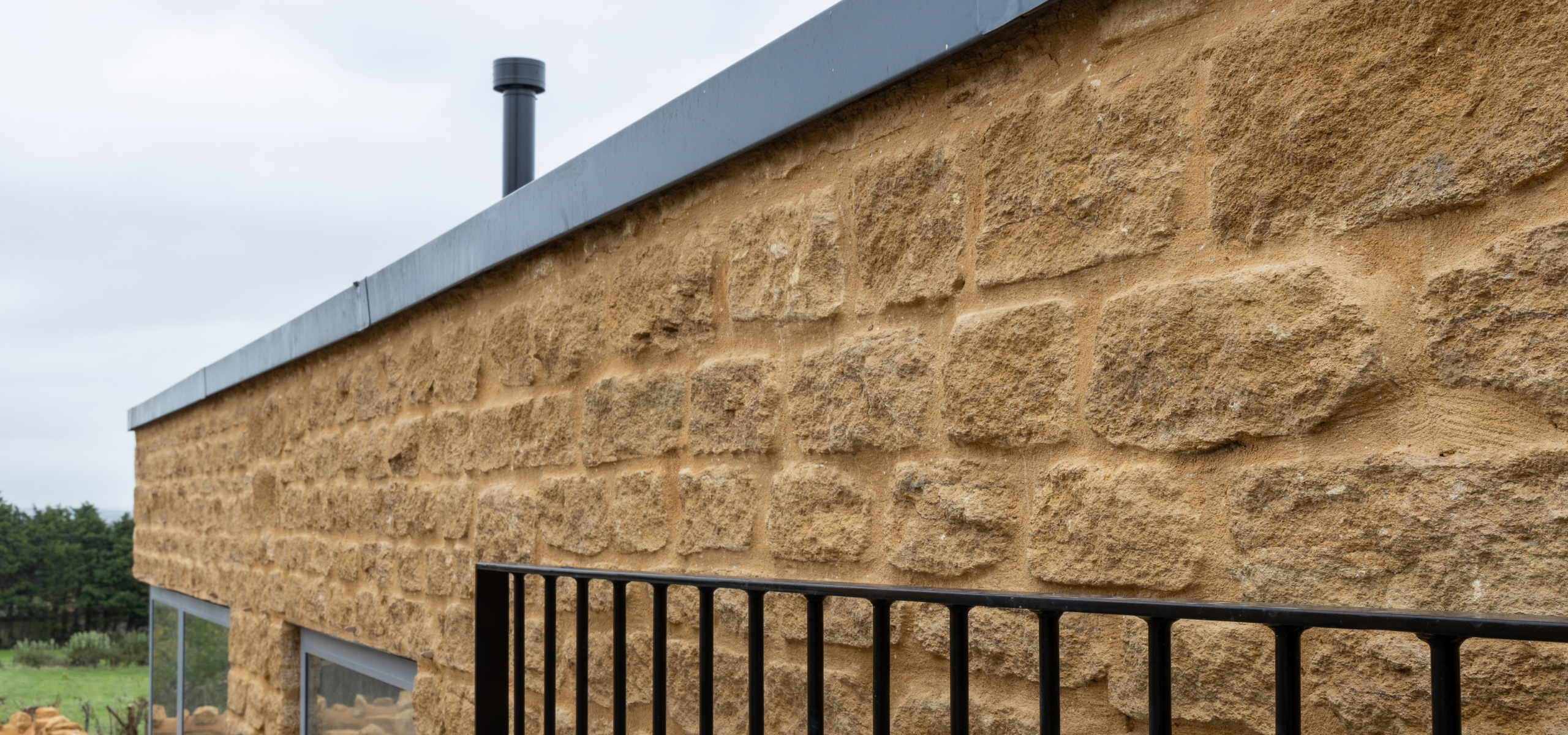 Hamstone brickwork with black metal gate and slate roof